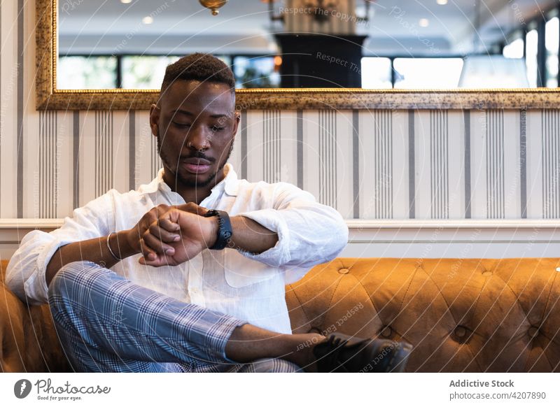 Stilvoller schwarzer Mann, der die Zeit auf seiner Armbanduhr überprüft prüfen warten trendy ernst punktuell Ernennung Geschäftsmann Afroamerikaner ethnisch