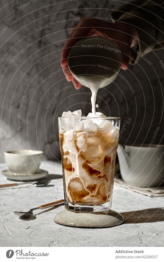 Eiskaffee mit Milch im Glas Kaffee melken eingießen kalt trinken vorbereiten Getränk Hand liquide lecker geschmackvoll Koffein Sonnenlicht Aroma dienen Morgen