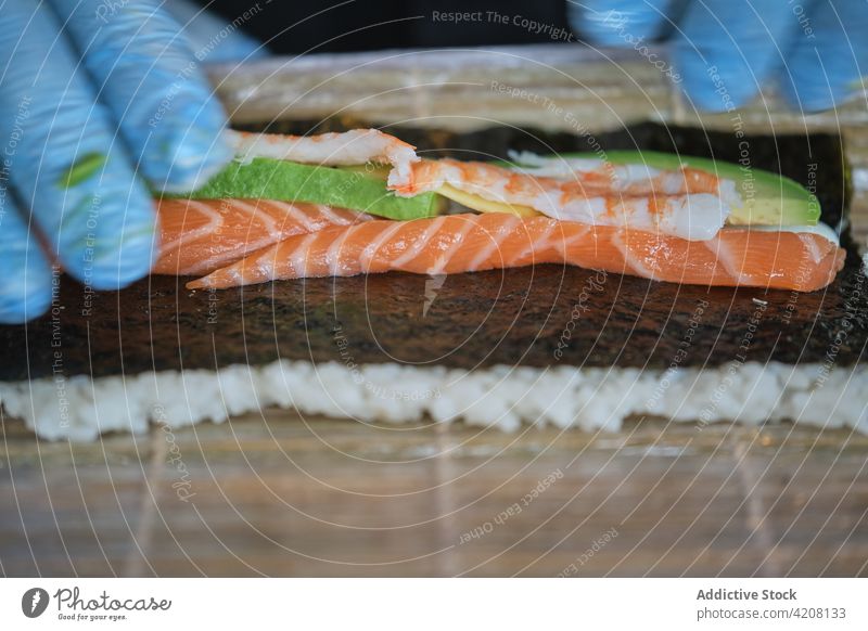 Detail eines Kochs bei der Zubereitung von Sushi Küchenchef Essen zubereiten vorbereitend rollen Seegras Lachs Fisch unerkannt japanisches Restaurant