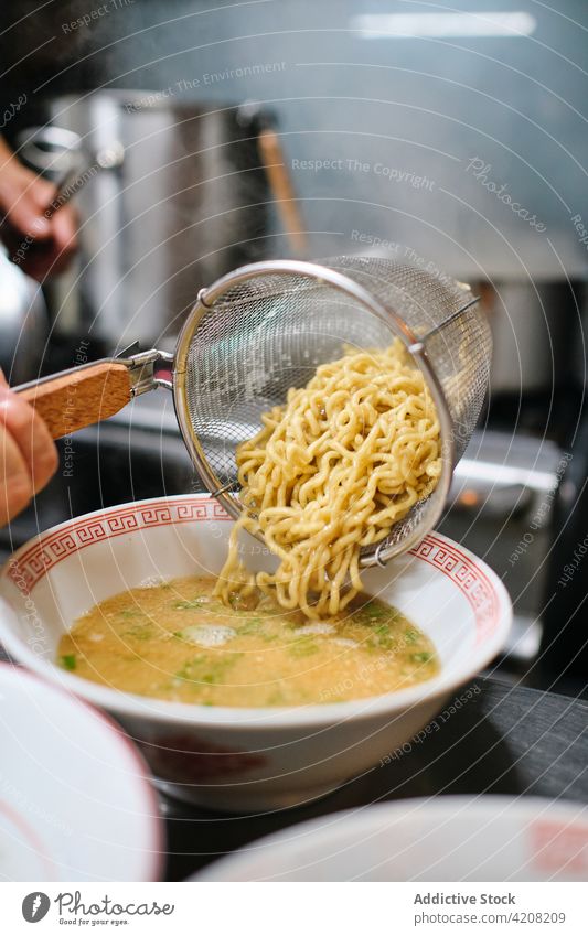 Detail der Nudelsuppenzubereitung Ramen Restaurant Küche Suppe Nudeln lecker Japanisches Essen Teller Sieb unerkannt Vorderansicht gesichtslos Gießen asiatisch
