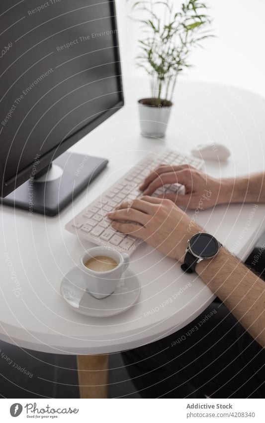 Anonymer Mann arbeitet am Computer in einem modernen Büro Tippen Keyboard Arbeit Mitarbeiter Job Internet online eingetopft Pflanze Tisch männlich Smartphone
