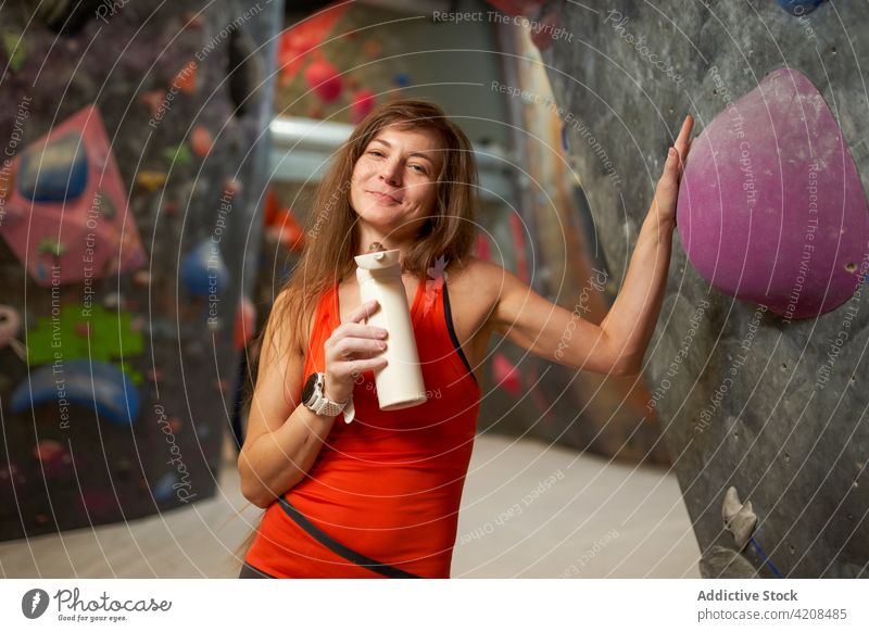 Glückliche Frau mit Wasser im Kletterzentrum Athlet Aufsteiger Fitnessstudio anlehnen Lächeln Erholung Pause Sport Gesundheit Training Bouldern Bergsteiger