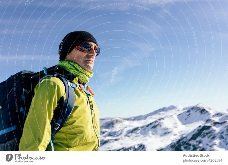 Reisende mit Rucksack bewundern schneebedeckte Berge Reisender Bergsteiger Schnee Mann Felsen aktiv Aufsteiger Sonnenlicht Natur Freiheit männlich Sportkleidung