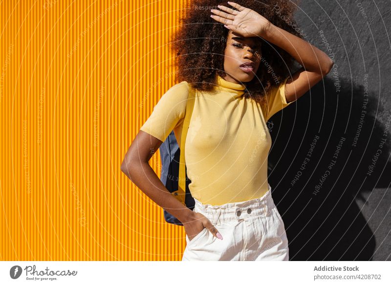 Trendy schwarze Frau steht auf gelben und schwarzen Hintergrund Afro-Look Frisur farbenfroh Porträt hell Afroamerikaner ethnisch trendy charismatisch