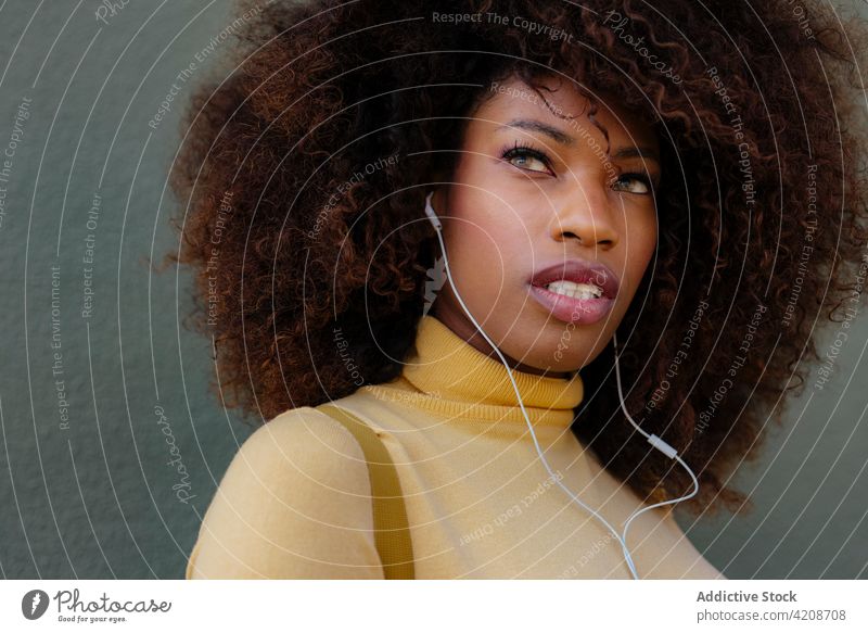 Verträumte schwarze Frau, die mit Kopfhörern Musik hört zuhören verträumt freie Zeit herzlich Afro-Look Porträt benutzend Gerät Gesang Frisur charmant wehmütig