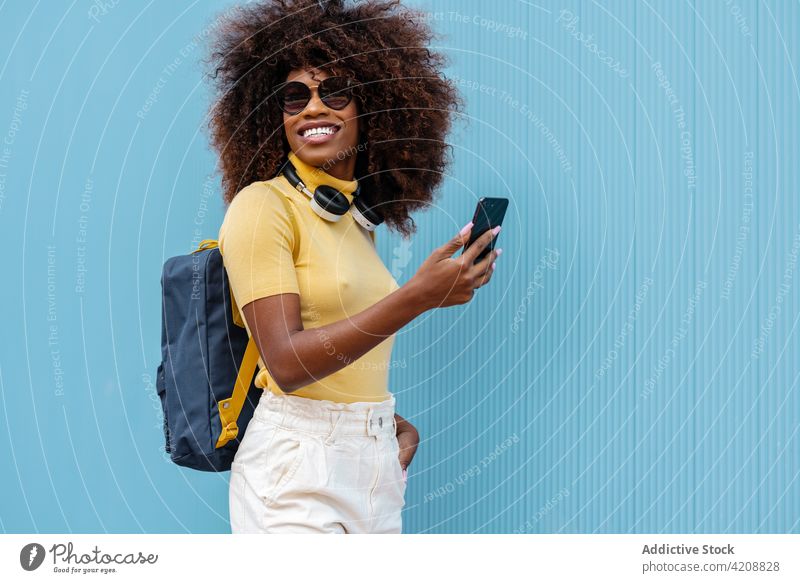 Fröhliche schwarze Frau, die ein Selfie mit ihrem Smartphone im Sonnenlicht macht Browsen Gedächtnis Moment Inhalt Kopfhörer Porträt benutzend Apparatur