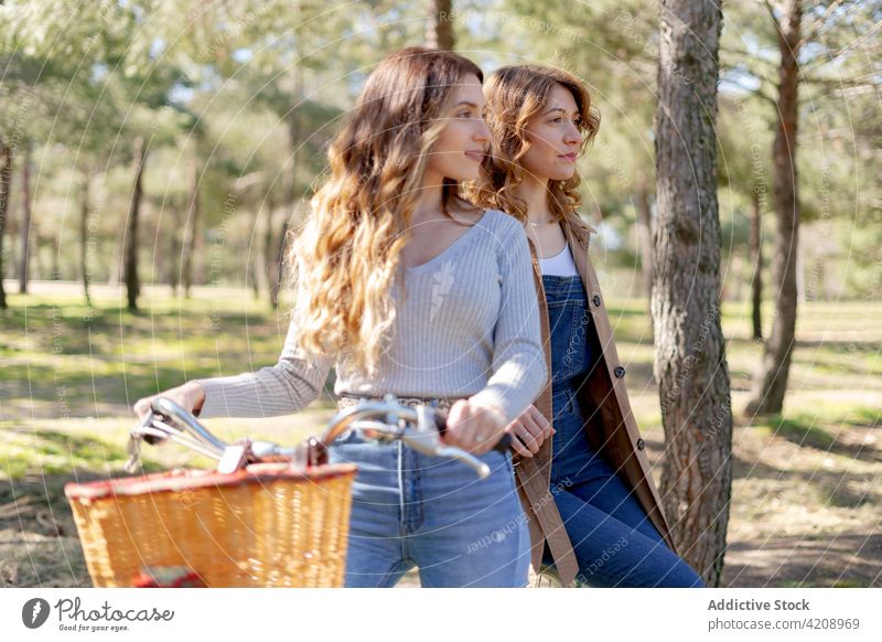 Fröhliche Frauen lächelnd auf dem Fahrrad im Park heiter Freundin Natur Glück Optimist Sommer sonnig Zusammensein jung positiv Freizeit Freude Wochenende