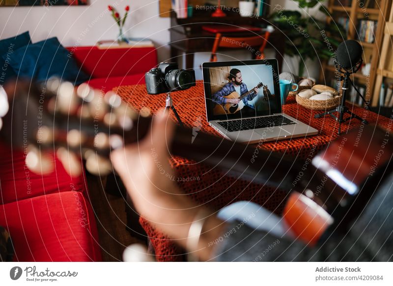 Hispanischer Gitarrist spielt Gitarre, während er sich ein Video auf dem Laptop ansieht Gitarrenspieler spielen Lektion lernen Mann benutzend Apparatur Gerät