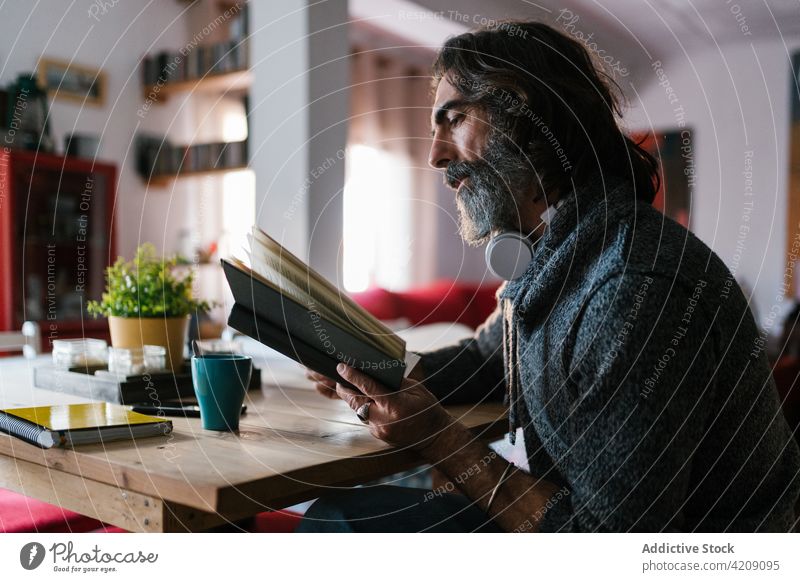 Älterer hispanischer Mann liest Buch im Haus Zimmer lesen Lehrbuch Literatur Weisheit Wissen Zeitvertreib Wochenende Porträt interessiert heimwärts Bildung