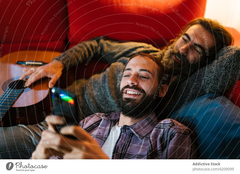 Inhalt Hispanischer Vater mit Sohn teilt Smartphone auf Sofa teilen Zeit verbringen Wochenende Lächeln Porträt benutzend Apparatur Männer Gerät Zusammensein