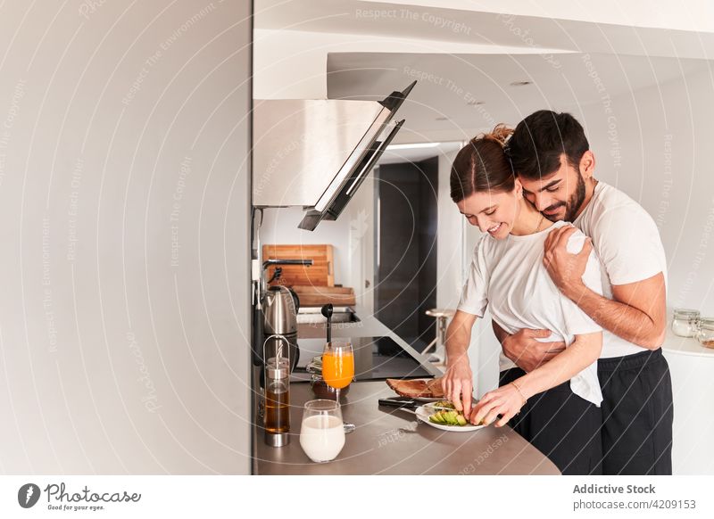 Liebendes junges gemischtrassiges Paar umarmt sich in der Küche vor dem Frühstück Umarmung Avocado Lächeln romantisch Zusammensein Partnerschaft Glück