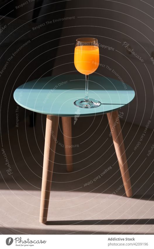 Glas mit frischem Saft auf einem kleinen Tisch in einer modernen Wohnung orange Gesundheit natürlich Entzug trinken Appartement Design geschmackvoll organisch