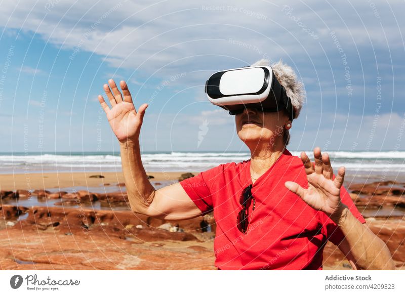 Unerkennbarer älterer Tourist mit VR-Headset am Meeresstrand Virtuelle Realität Erfahrung unterhalten Technik & Technologie modern Meeresufer Frau benutzend