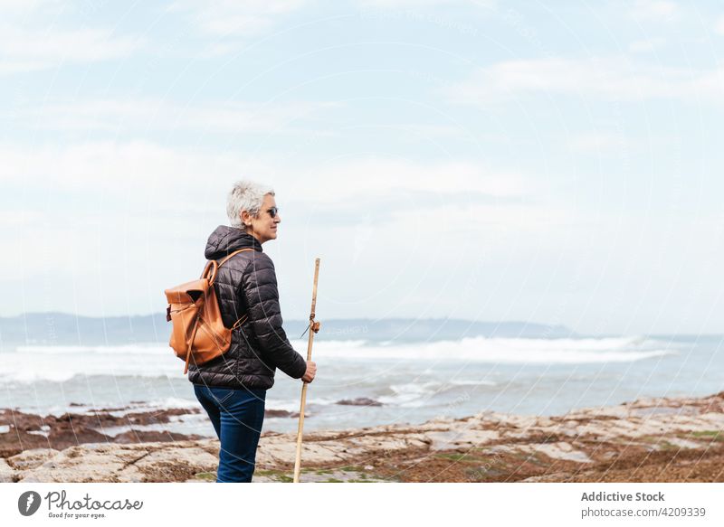 Älterer Wanderer bei einem Spaziergang am felsigen Meeresstrand Trekker Strand MEER Felsbrocken Mast Ausflug erkunden Fernweh Frau Meereslandschaft Natur