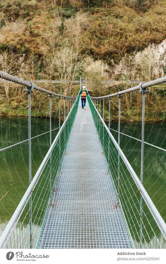 Älterer Reisender, der auf einer Hängebrücke gegen üppige Bäume läuft Wanderer Suspension Brücke Route Regie erkunden Spaziergang Fernweh Natur Frau vegetieren
