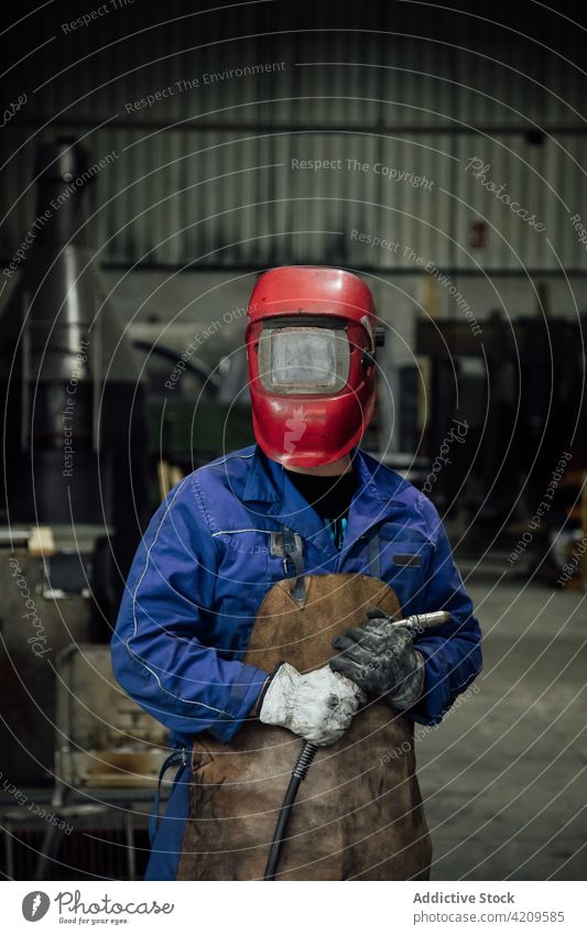 Unbekannter Schweißer mit Schutzhelm und Schweißschlauch in der Garage Person Mechaniker Handwerker Werkstatt Arbeiter Spezialist Gerät Uniform Konstruktion