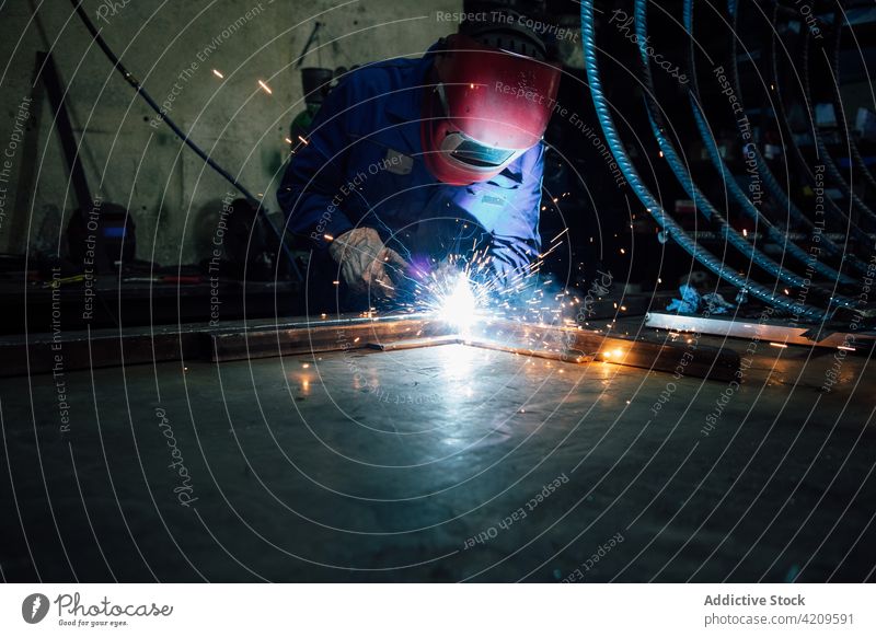 Anonymer Arbeiter beim Schweißen einer Metallkonstruktion in einer Werkstatt Person Schweißnaht Handwerker Funken Konstruktion Gerät professionell Ingenieur