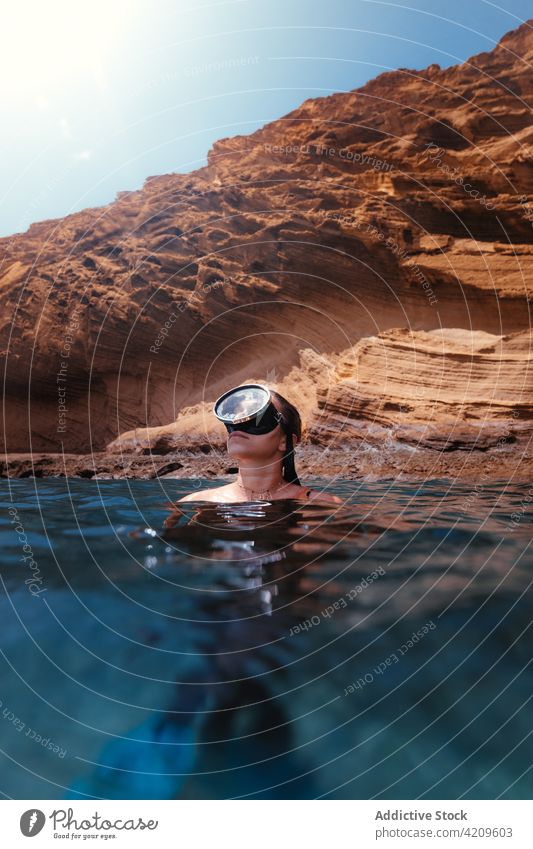Frau schwimmt im Meer gegen eine Felsklippe Tourist Wasser MEER felsig Klippe Hobby blau Ausflug Urlaub Reisender Mundschutz Sauberkeit reisen Erholung erkunden