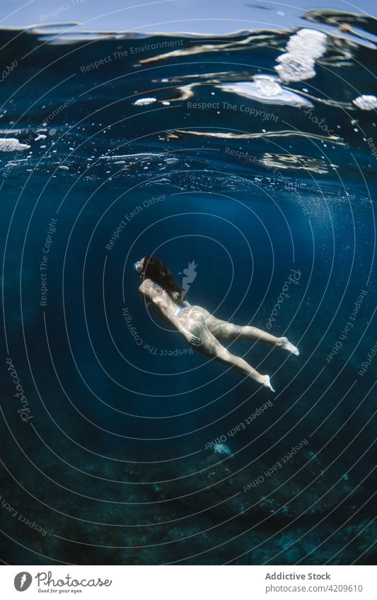 Frau in Badekleidung schwimmt unter Wasser schwimmen Urlaub Feiertag Resort MEER tropisch exotisch reisen Sauberkeit Badeanzug tief Sonnenlicht aqua