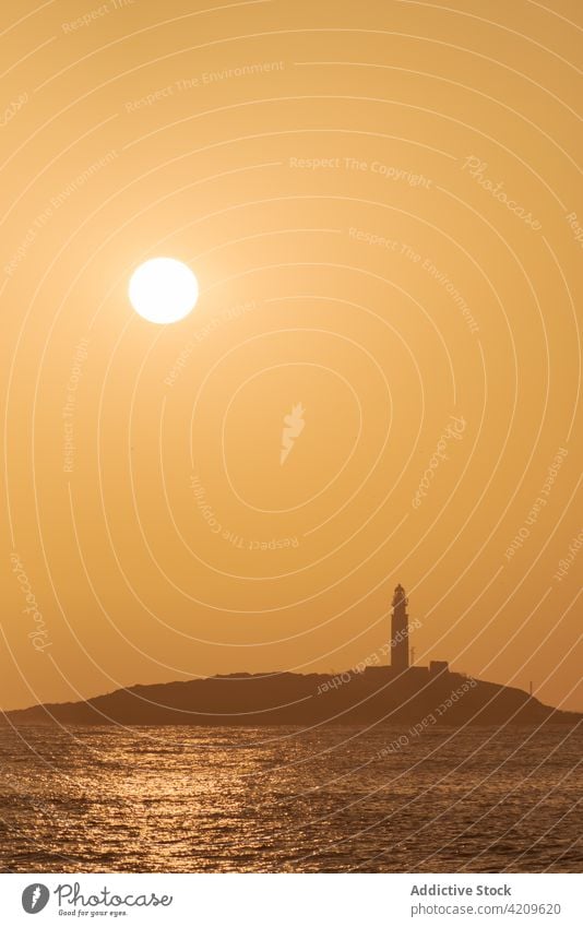 Heller Sonnenuntergang über Meer und Küste mit Leuchtturm Ufer Sonnenaufgang Rippeln hell Wasser Umwelt Faro de Trafalgar Cadiz Spanien hoher Anstieg malerisch