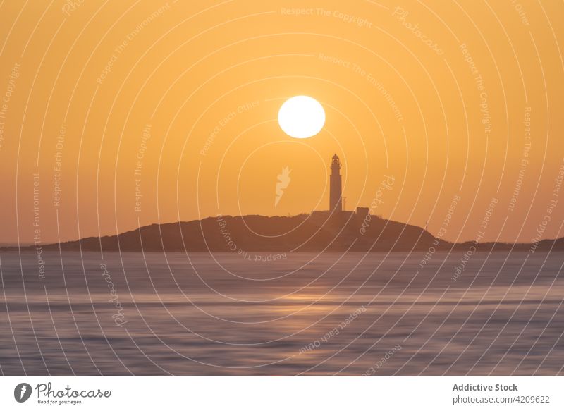 Heller Sonnenuntergang über Meer und Küste mit Leuchtturm Ufer Sonnenaufgang Rippeln hell Wasser Umwelt Faro de Trafalgar Cadiz Spanien hoher Anstieg malerisch