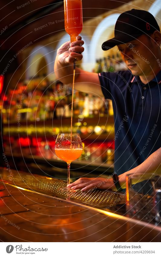 Junger asiatischer Barkeeper gießt Grapefruitsaft in ein Glas, während er einen Cocktail in der Bar zubereitet Alkohol alkoholisch Aperitif Barista Barmann