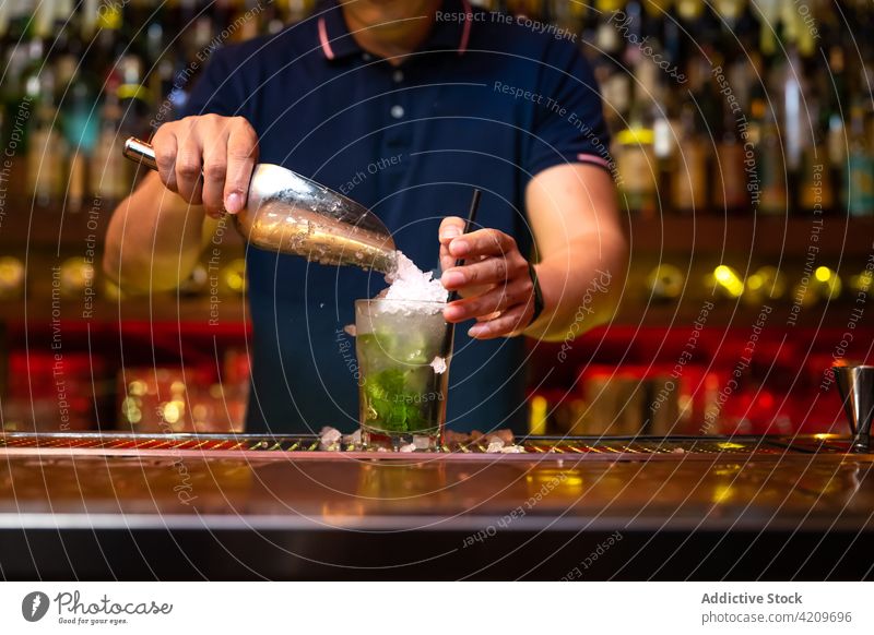 Unbekannter Barkeeper gießt zerstoßenes Eis in das Glas, während er einen Cocktail in der Bar zubereitet Alkohol alkoholisch Aperitif Barista Barmann Getränk