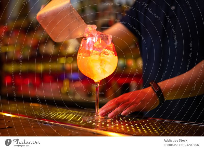 Unbekannter Barkeeper, der bei der Zubereitung eines Cocktails in der Bar Eiswürfel in das Glas gibt Alkohol alkoholisch Aperitif Barista Barmann Getränk