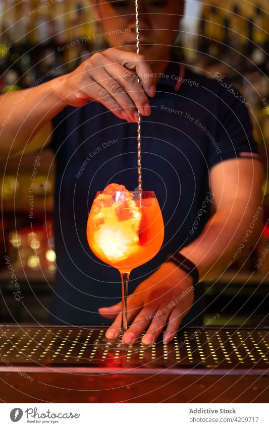 Junge asiatische Barkeeperin rührt in der Bar einen Gin-Cocktail mit Grapefruitsaft Alkohol alkoholisch Aperitif Barista Barmann Getränk Flasche Business