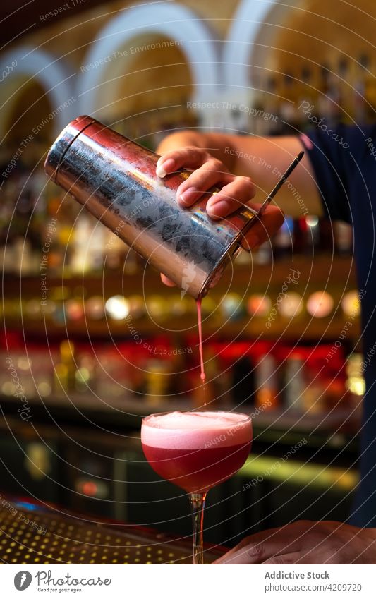 Detail der Hand des Barkeepers, der in der Bar mit seinem Shaker arbeitet und einen Cocktail in ein Glas gießt Alkohol alkoholisch Aperitif Barista Barmann