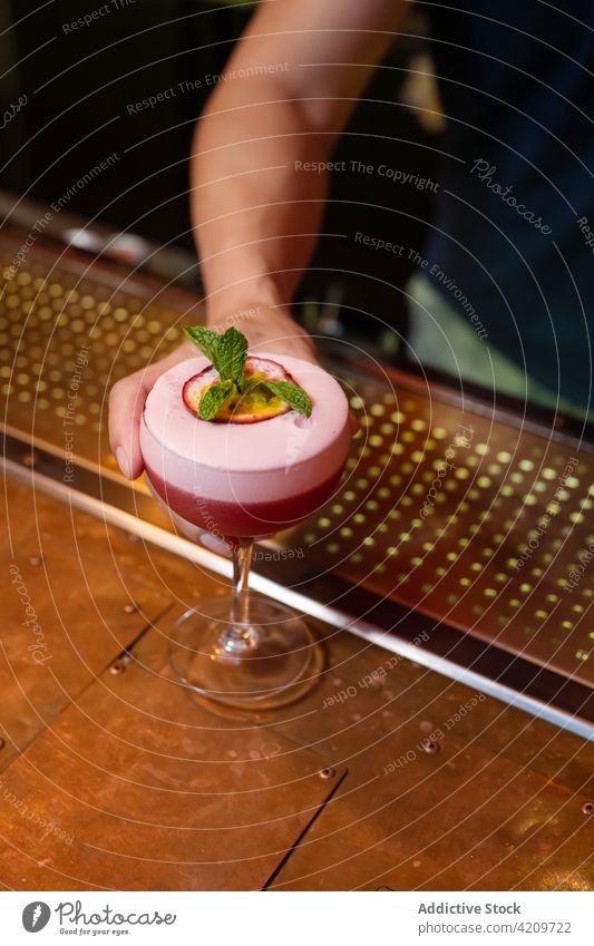 Unbekannter Barkeeper serviert einen Cocktail mit Minzblättern und Passionsfrucht in der Bar Alkohol alkoholisch Aperitif Barista Barmann Getränk Business Club