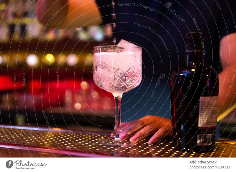 Junger asiatischer Barkeeper gießt Tonic Water in ein Glas, um einen Gin-Tonic-Cocktail in der Bar zuzubereiten Alkohol alkoholisch Aperitif Barista Barmann