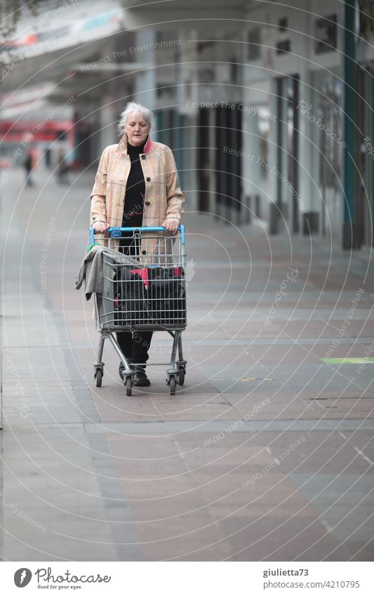 Frau mit Mantel und Einkaufswagen beim einsamen Einkaufsbummel-Spaziergang Mensch Porträt Außenaufnahme Erwachsene Einsamkeit Einkaufszentrum Einkaufen Konsum