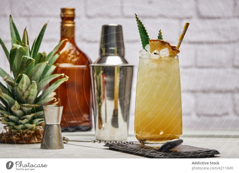 Glas mit Ananas-Cocktail beim Shaker Eis Schiefer Würfel Stroh Schüttler Abfertigungsschalter Löffel Blatt Glaswaren kreativ frisch Papier Untersetzer exotisch