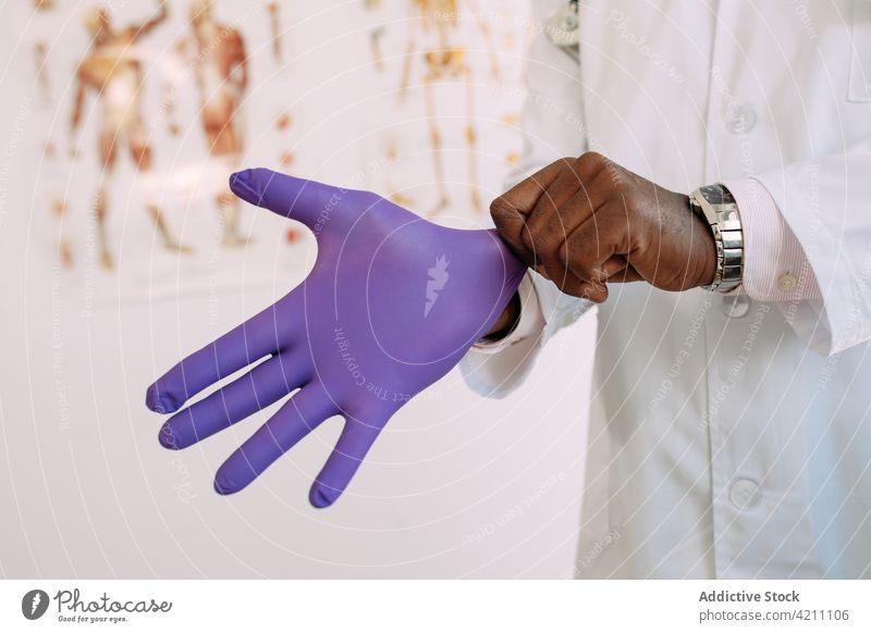 Schwarzer Mann trägt Latexhandschuh im Krankenhaus anhaben Handschuh steril medizinisch Sauberkeit professionell behüten Uniform männlich Arzt Job schwarz