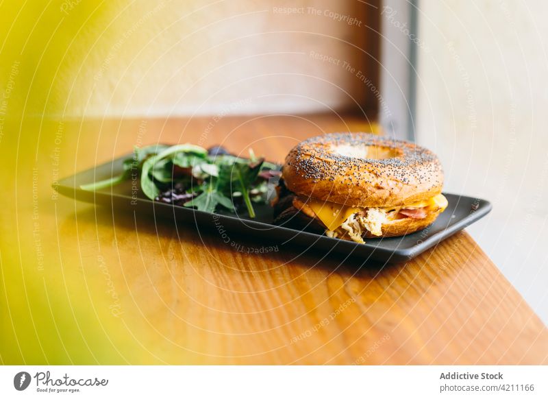 Leckeres Bagel-Sandwich auf dem Tisch im Café Belegtes Brot Fleisch dienen geschmackvoll Hähnchen appetitlich Lebensmittel Mahlzeit lecker Salatbeilage Teller