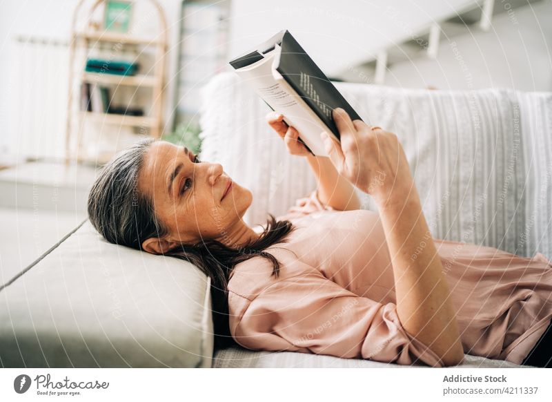Konzentrierte Frau, die auf der Couch ein Buch liest lesen Liege Sofa Appartement heimisch Hobby Leseratte Wohnzimmer liegend heimwärts lässig Konzentration