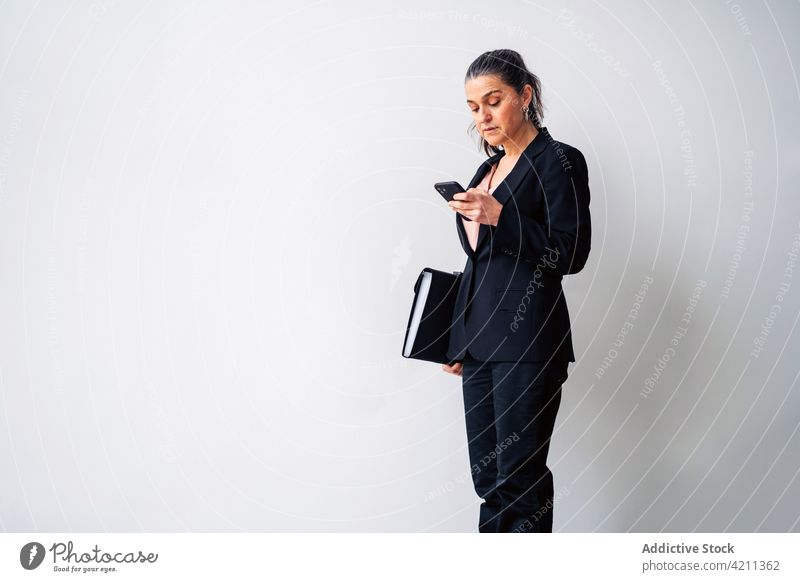 Selbstbewusste reife Frau im Anzug beim Surfen auf dem Smartphone Browsen Textnachricht Mappe Unternehmer formal Manager Schriftstück respektabel Business SMS