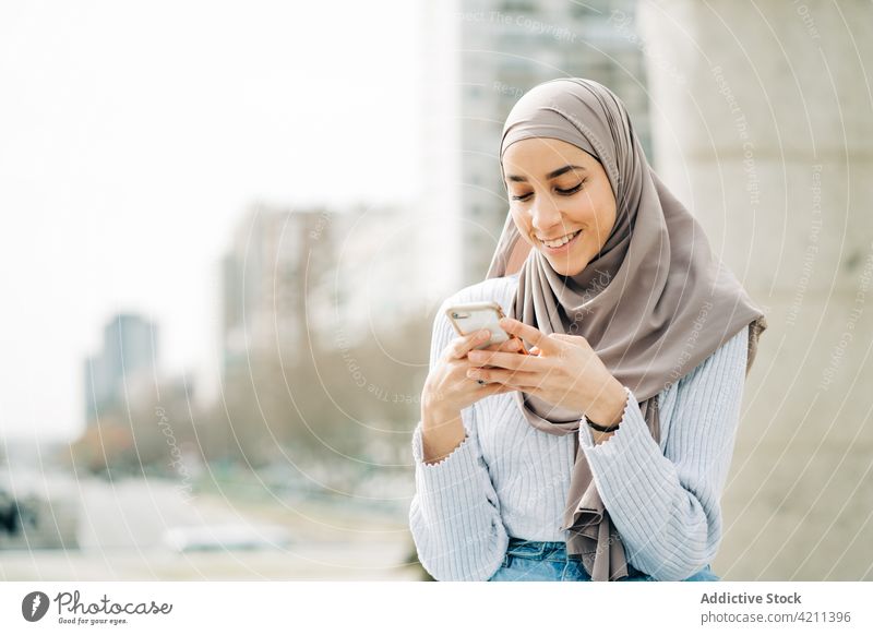 Muslimische Frau benutzt Smartphone auf der Straße Browsen Großstadt Nachricht soziale Netzwerke jung Hijab Tradition ethnisch muslimisch Telefon Mobile