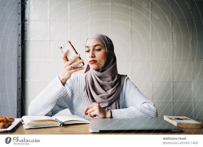 Muslimische Unternehmerin nimmt Sprachnachricht auf Smartphone auf Frau Aufzeichnen Stimme Nachricht Audio Arbeit freiberuflich Café benutzend ethnisch