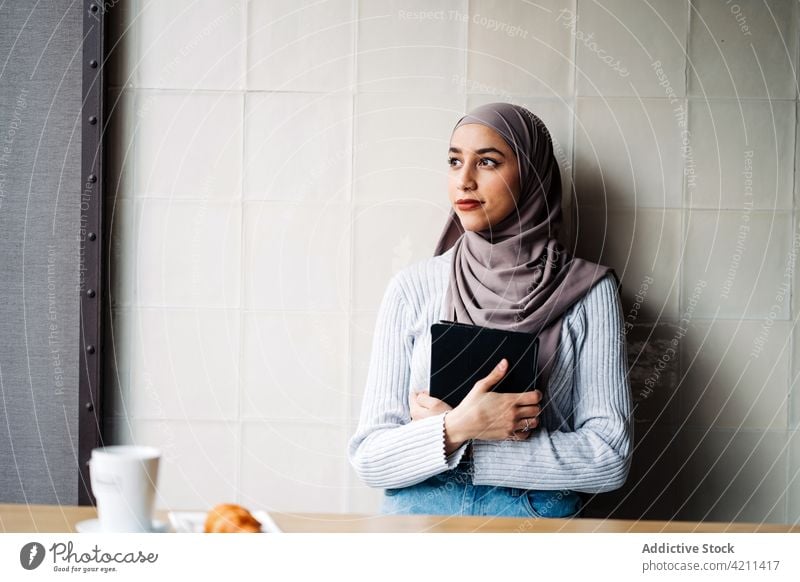 Ethnische Frau mit Kopftuch benutzt Tablet in einem Cafe Browsen Tablette freiberuflich Café Arbeit Projekt Surfen benutzend Hijab ethnisch muslimisch Apparatur