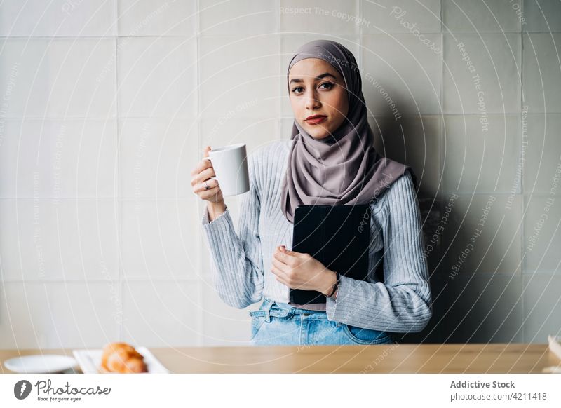 Porträt einer muslimischen Frau mit Getränk und Tablette in einem Cafe Café freiberuflich Arbeit nachdenklich Tasse trinken besinnlich Hijab ethnisch Projekt