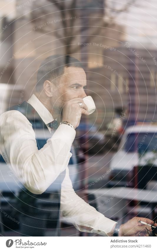 Stilvoller ethnischer Geschäftsmann trinkt Kaffee in einer Cafeteria trinken formal maskulin Heißgetränk Reflexion & Spiegelung Glaswand Café Mann Unternehmer