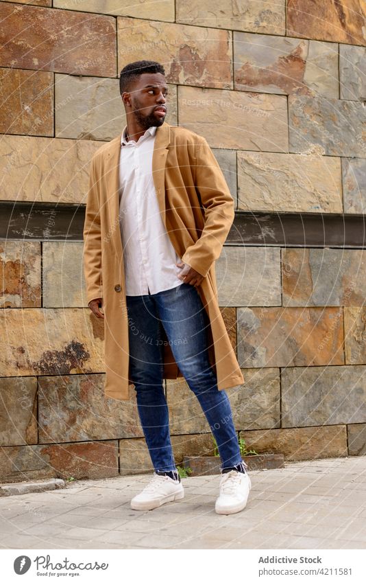 Stilvoller schwarzer Mann steht auf der Straße und schaut weg Mantel Großstadt trendy Outfit gutaussehend Bekleidung urban männlich ethnisch Afroamerikaner