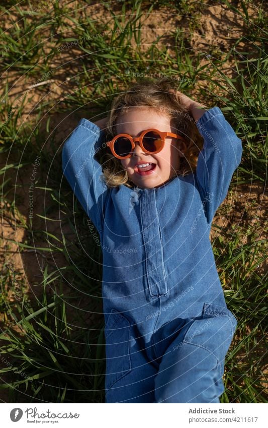 Stilvolles Mädchen auf Gras liegend ruhen Outfit Feld Rasen Wochenende Hand hinter dem Kopf Sommer Kind Saison Sonnenbrille trendy friedlich Kälte sorgenfrei