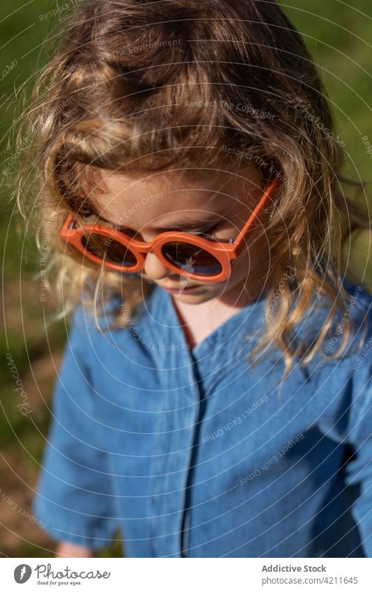 Stilvolles Mädchen im Gras stehend ruhen Outfit Feld Rasen Sommer Kind Saison Sonnenbrille trendy friedlich Kälte Kleidungsstück Bekleidung Accessoire Park
