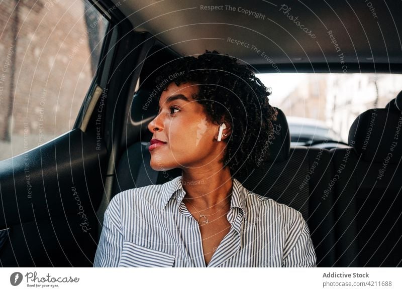 Junge schwarze Beifahrerin auf der Rückbank im Auto liegend Frau zuhören Musik PKW Passagier tws echte drahtlose Ohrstöpsel Sitz Glück Lächeln Arbeitsweg Kälte