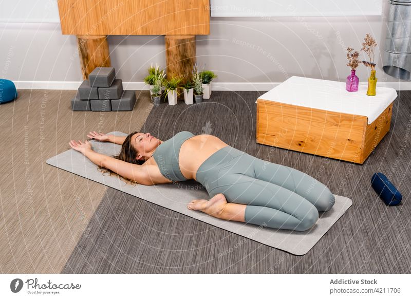 Entspannte junge Frau auf Matte liegend Erweiterte Supine Hero Yoga-Asana erweiterter Rückenheld utthita supta virasana Augen geschlossen Erholung Stressabbau