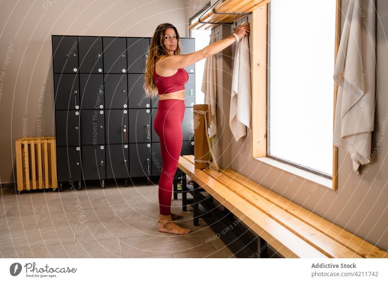 Sportlerin nimmt Handtuch im Umkleideraum des Fitnessstudios nach dem Training Sportkleidung Raum Spind sportlich Wellness physisch Frau Sportbekleidung