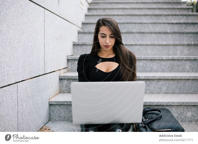 Geschäftsfrau tippt auf einem Laptop in der Stadt Tippen Großstadt Arbeit abgelegen Browsen Entfernung Projekt online Frau Unternehmer Stein sitzen Treppe